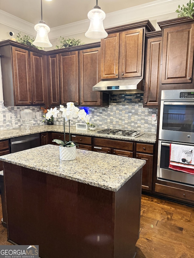 1869 Schofield Dr, Hampton, GA 30228 - kitchen with stainless steel appliances, under cabinet range hood, crown molding, a center island, and decorative light fixtures