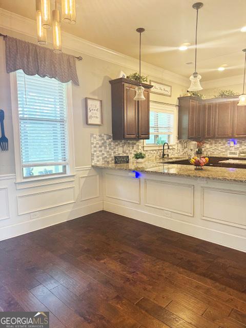 1869 Schofield Dr, Hampton, GA 30228 - kitchen featuring a chandelier, ornamental molding, light stone countertops, a wainscoted wall, and dark wood-style floors