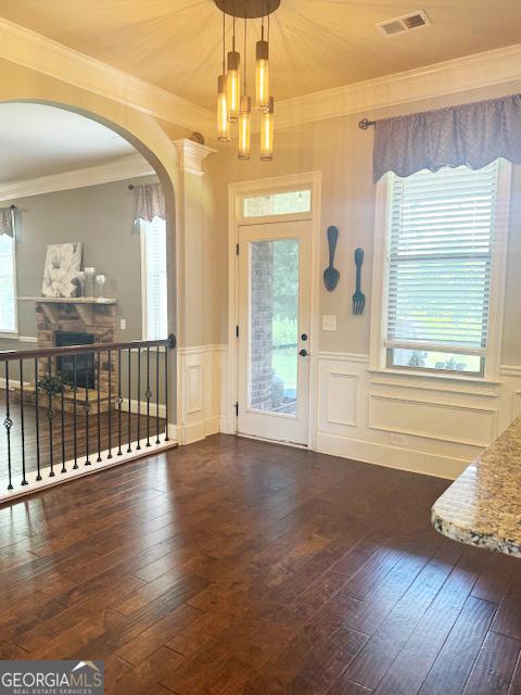 1869 Schofield Dr, Hampton, GA 30228 - foyer featuring arched walkways, a chandelier, hardwood / wood-style flooring, a wainscoted wall, and crown molding
