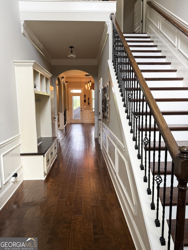 1869 Schofield Dr, Hampton, GA 30228 - stairs featuring arched walkways, a decorative wall, crown molding, hardwood / wood-style floors, and wainscoting