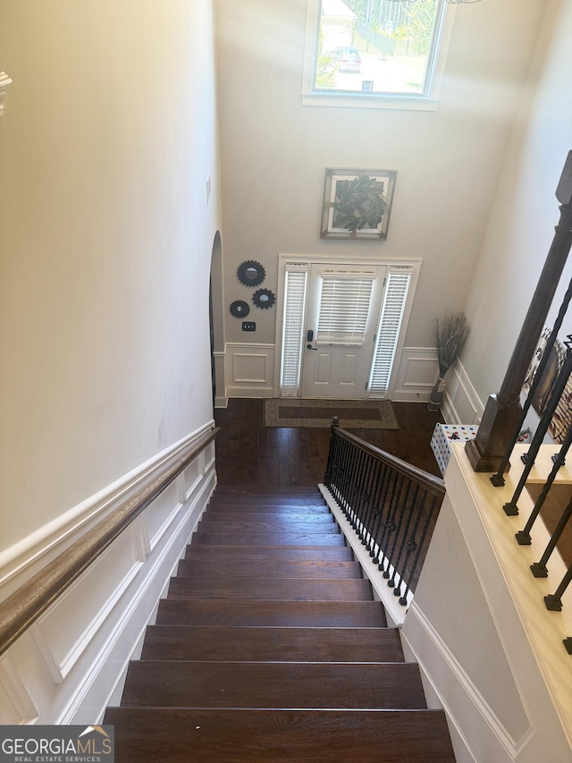 1869 Schofield Dr, Hampton, GA 30228 - stairs with a decorative wall, a towering ceiling, arched walkways, a wainscoted wall, and wood finished floors