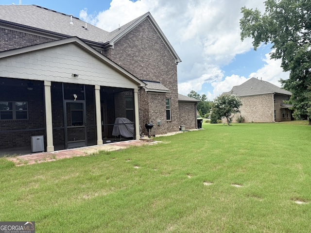 1869 Schofield Dr, Hampton, GA 30228 - back of house featuring a sunroom, a yard, brick siding, and roof with shingles