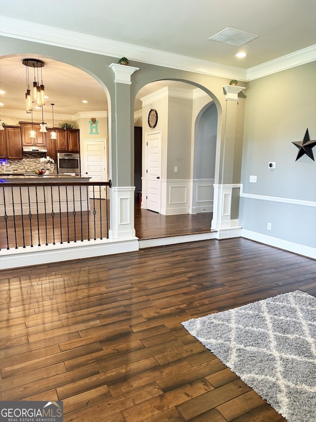 1869 Schofield Dr, Hampton, GA 30228 - unfurnished living room with dark wood-type flooring, crown molding, wainscoting, arched walkways, and recessed lighting