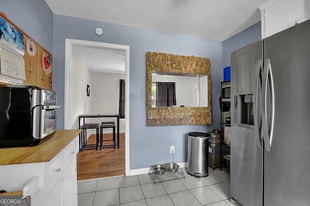 4110 Belvedere Dr, Gainesville, GA 30506 - kitchen with appliances with stainless steel finishes, butcher block counters, light tile patterned floors, white cabinets, and baseboards