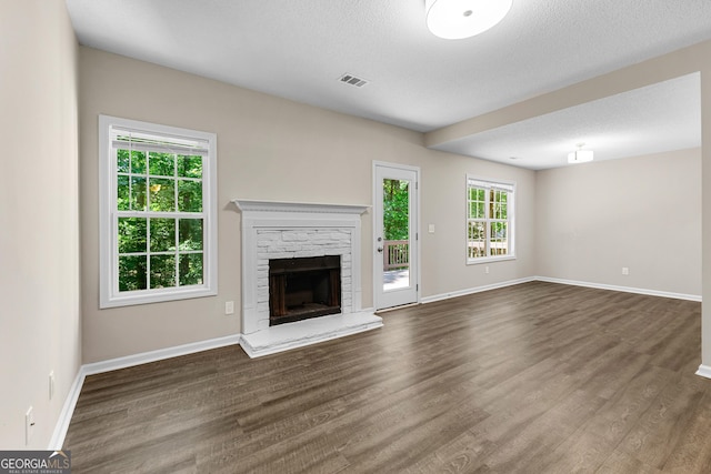 80 Corn Row Ct, Newnan, GA 30263 - unfurnished living room with dark wood-type flooring, a stone fireplace, baseboards, and a textured ceiling