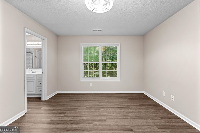 80 Corn Row Ct, Newnan, GA 30263 - unfurnished bedroom featuring a textured ceiling, dark wood-type flooring, a sink, baseboards, and connected bathroom