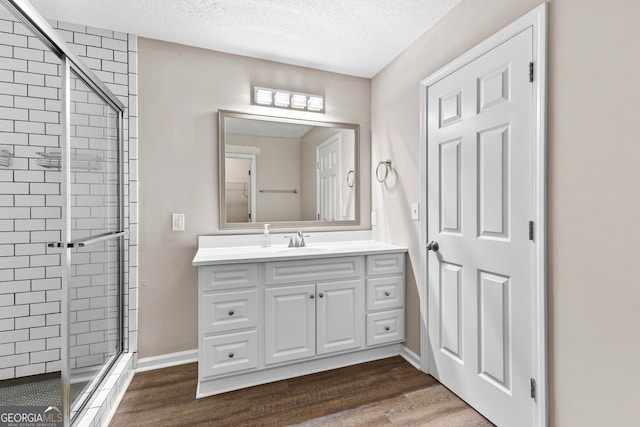 80 Corn Row Ct, Newnan, GA 30263 - full bathroom with a shower stall, wood finished floors, a textured ceiling, vanity, and baseboards