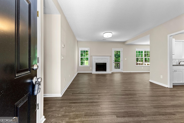 80 Corn Row Ct, Newnan, GA 30263 - unfurnished living room featuring dark wood finished floors, baseboards, and a fireplace with raised hearth
