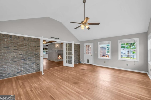 3642 S Bogan Rd, Buford, GA 30519 - unfurnished living room with a ceiling fan, a fireplace, wood finished floors, high vaulted ceiling, and brick wall
