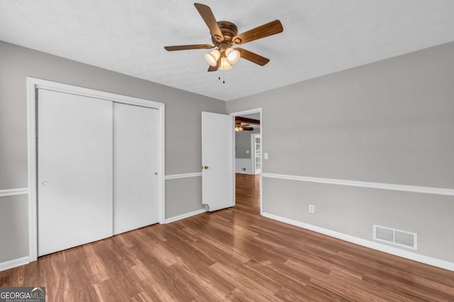 3642 S Bogan Rd, Buford, GA 30519 - unfurnished bedroom with wood finished floors, baseboards, a closet, and a ceiling fan