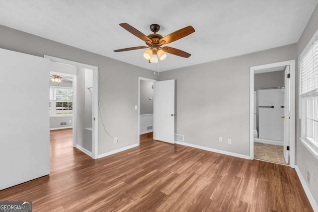 3642 S Bogan Rd, Buford, GA 30519 - unfurnished bedroom with wood finished floors, baseboards, and connected bathroom