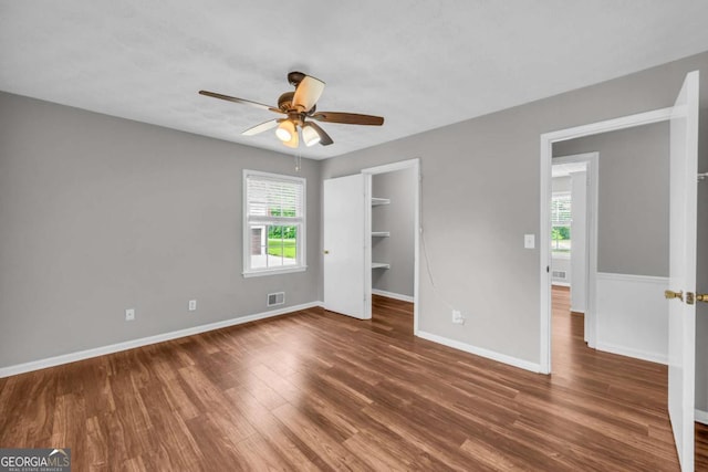3642 S Bogan Rd, Buford, GA 30519 - unfurnished bedroom featuring wood finished floors, baseboards, a spacious closet, a ceiling fan, and a closet