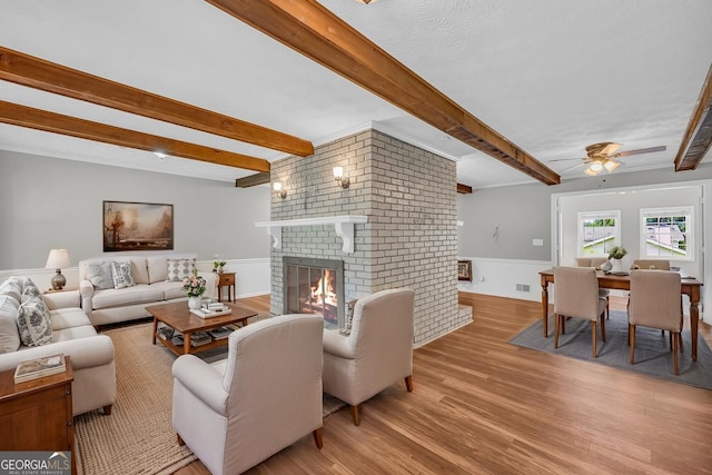 3642 S Bogan Rd, Buford, GA 30519 - living area with wood finished floors, beamed ceiling, a fireplace, a wainscoted wall, and a ceiling fan