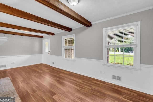 3642 S Bogan Rd, Buford, GA 30519 - unfurnished living room featuring healthy amount of natural light, wood finished floors, wainscoting, and beam ceiling