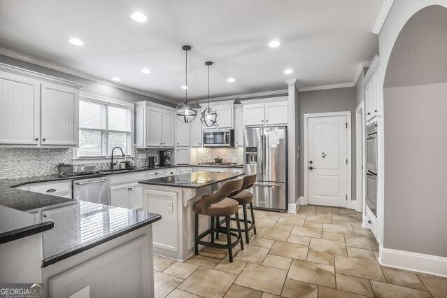 4818 Moon Hollow Ct, Buford, GA 30519 - kitchen featuring stainless steel appliances, crown molding, dark countertops, tasteful backsplash, and a kitchen island