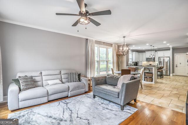 4818 Moon Hollow Ct, Buford, GA 30519 - living room featuring a chandelier, crown molding, a ceiling fan, and recessed lighting