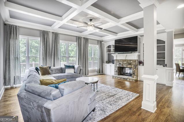 4818 Moon Hollow Ct, Buford, GA 30519 - living area with ornate columns, healthy amount of natural light, a stone fireplace, ceiling fan, and coffered ceiling