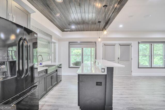 4818 Moon Hollow Ct, Buford, GA 30519 - kitchen with black refrigerator with ice dispenser, baseboards, light wood-style flooring, stainless steel dishwasher, and light countertops