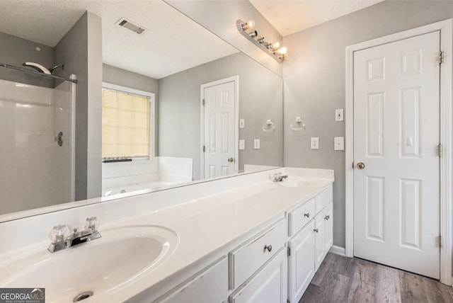 1478 Elena Dr, Mcdonough, GA 30253 - bathroom with double vanity, a shower, wood finished floors, a garden tub, and a textured ceiling