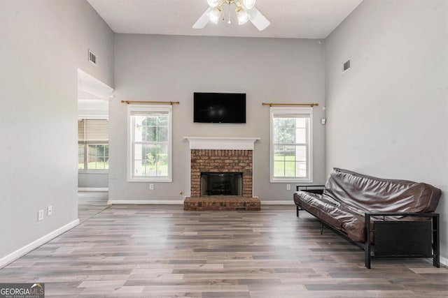 1478 Elena Dr, Mcdonough, GA 30253 - living room featuring ceiling fan, wood finished floors, a towering ceiling, and a brick fireplace