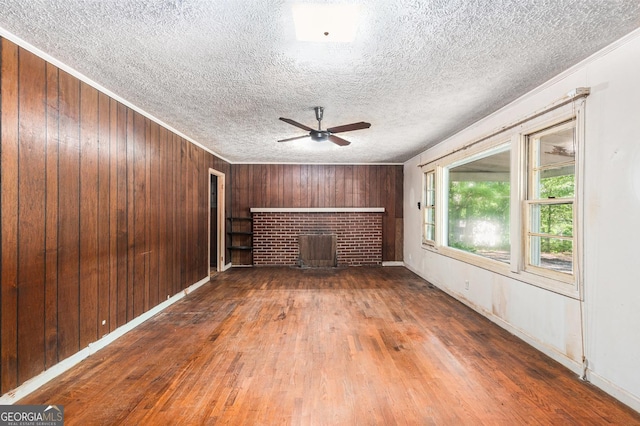 117 Chester Harris Dr, Dallas, GA 30132 - unfurnished living room featuring a fireplace, wood finished floors, a ceiling fan, a textured ceiling, and wooden walls
