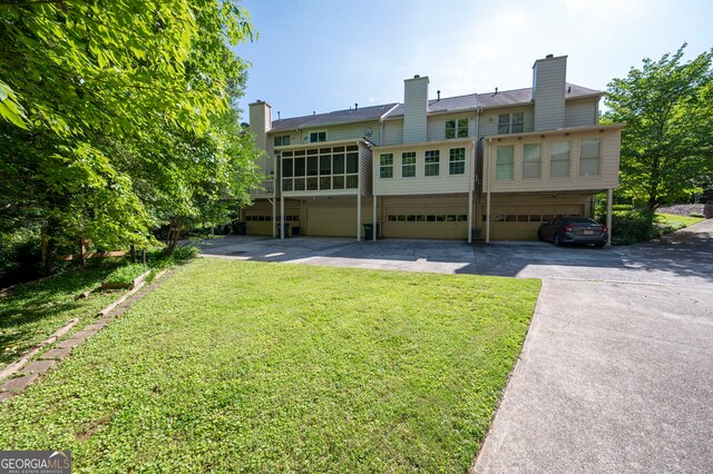 1223 Whitlock Ridge Dr SW, Marietta, GA 30064 - rear view of house with driveway, a garage, a yard, a chimney, and a sunroom