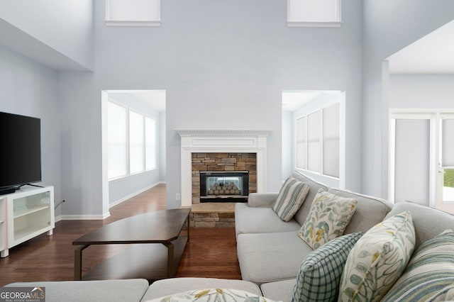130 Bevington Ln, Woodstock, GA 30188 - living room featuring a towering ceiling, healthy amount of natural light, dark wood-type flooring, a stone fireplace, and baseboards