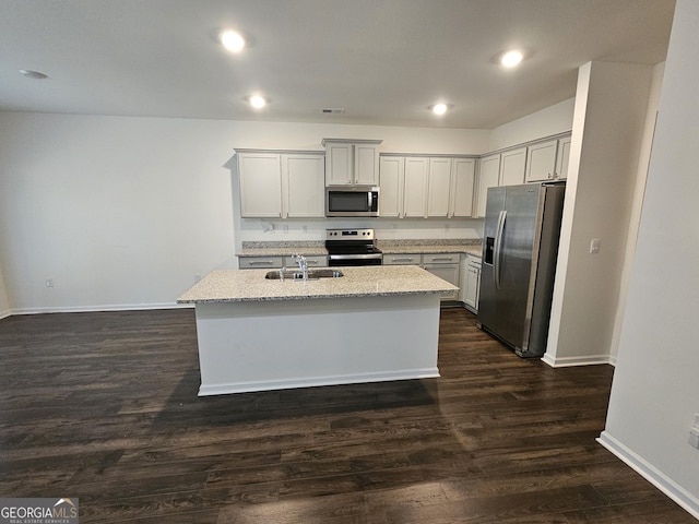 190 Hampton Cir, Mcdonough, GA 30253 - kitchen featuring stainless steel appliances, a sink, dark wood-style floors, a kitchen island with sink, and light stone countertops