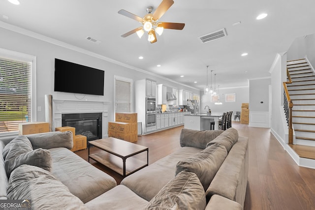 132 Shellbark Dr, Mcdonough, GA 30252 - living room with ornamental molding, a ceiling fan, light wood-style floors, stairs, and a glass covered fireplace