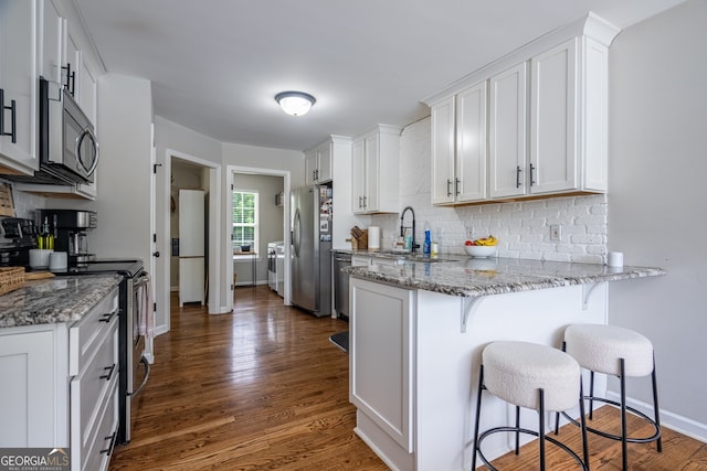 520 Campbell Rd, Cedartown, GA 30125 - kitchen featuring appliances with stainless steel finishes, tasteful backsplash, a peninsula, white cabinetry, and a kitchen breakfast bar