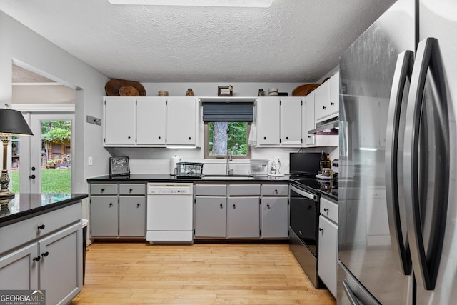 349 Campground Rd, Mcdonough, GA 30253 - kitchen featuring stainless steel appliances, a sink, dark countertops, light wood-style flooring, and under cabinet range hood