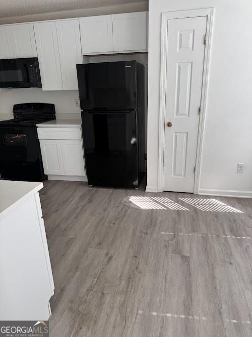 5709 Newnan Cir, Austell, GA 30106 - kitchen featuring black appliances, white cabinets, light wood finished floors, and baseboards