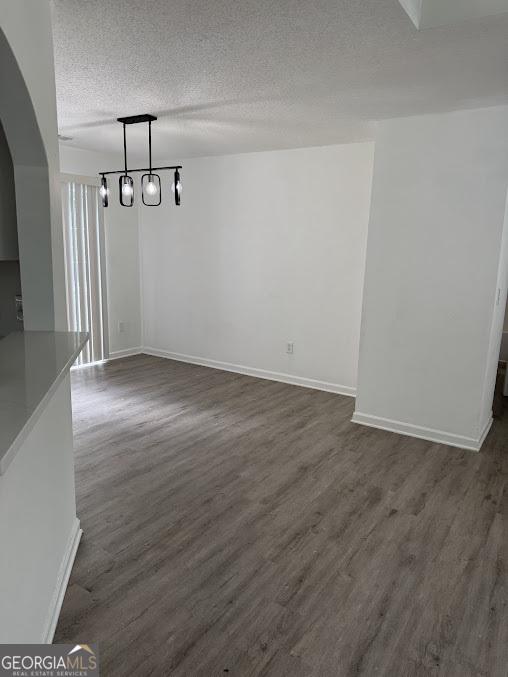 5709 Newnan Cir, Austell, GA 30106 - unfurnished dining area featuring a textured ceiling, dark wood finished floors, and baseboards