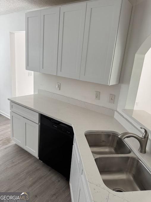 5709 Newnan Cir, Austell, GA 30106 - kitchen with black dishwasher, a sink, wood finished floors, white cabinetry, and light stone counters