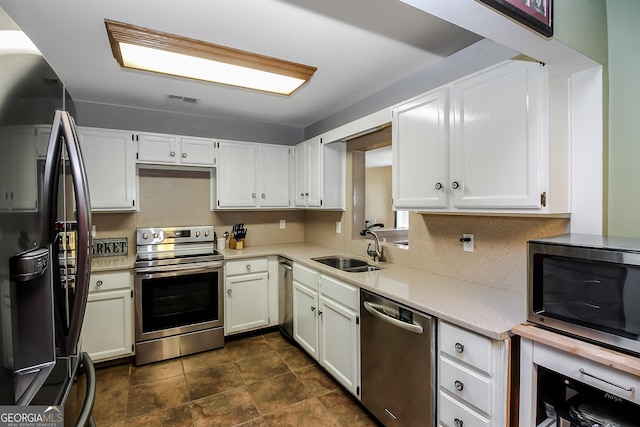 387 Colvin Dr, Locust Grove, GA 30248 - kitchen featuring appliances with stainless steel finishes, a sink, white cabinets, and light stone countertops