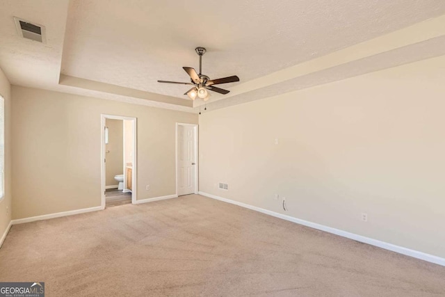 484 Cathedral Dr, Mcdonough, GA 30253 - unfurnished bedroom with baseboards, a tray ceiling, carpet floors, connected bathroom, and ceiling fan