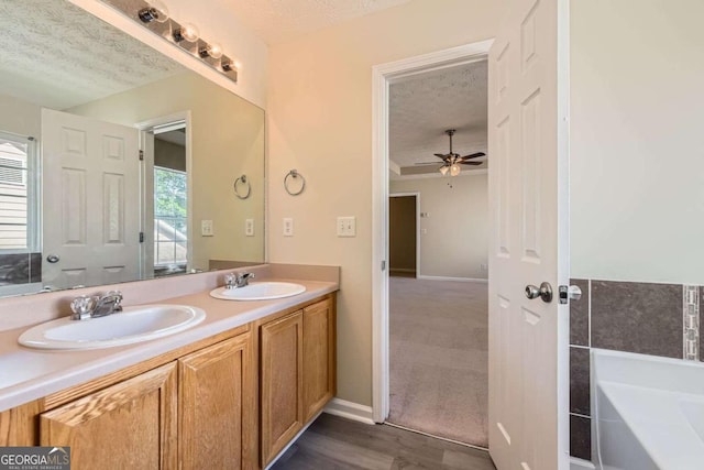 484 Cathedral Dr, Mcdonough, GA 30253 - full bath featuring a textured ceiling, double vanity, plenty of natural light, a garden tub, and ceiling fan