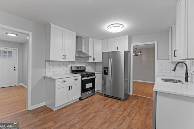 2002 Twin Falls Rd, Decatur, GA 30032 - kitchen with appliances with stainless steel finishes, wall chimney range hood, a sink, a chandelier, and wood finished floors