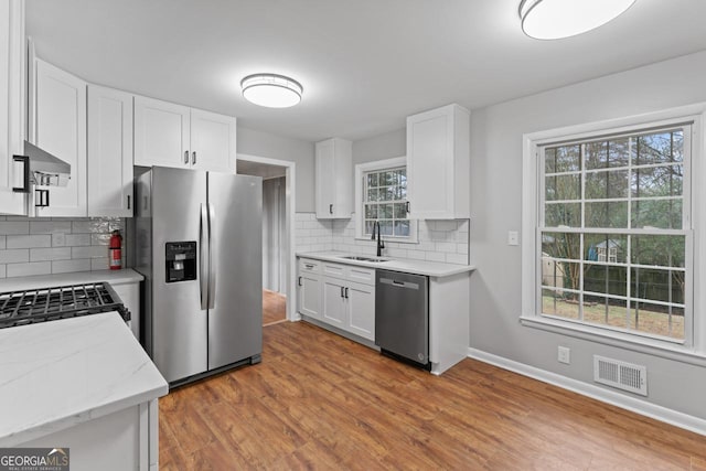 2002 Twin Falls Rd, Decatur, GA 30032 - kitchen with appliances with stainless steel finishes, a sink, tasteful backsplash, white cabinetry, and light wood-style floors