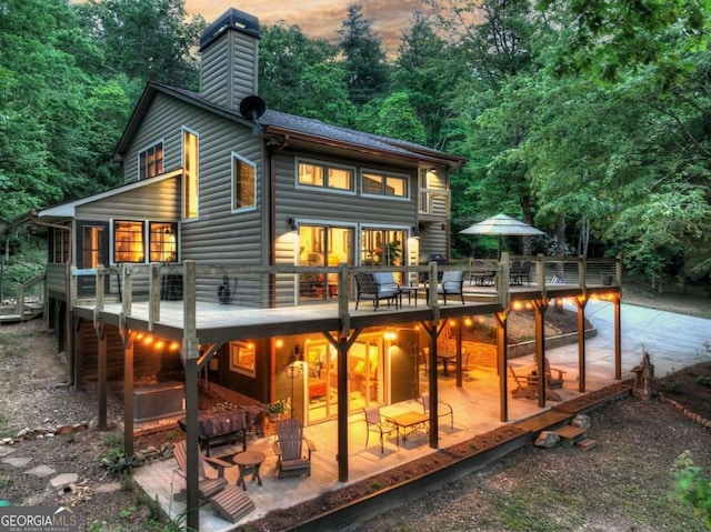 123 Old Fjord Rd, Blue Ridge, GA 30513 - back of house at dusk with a patio, a chimney, log veneer siding, and a wooden deck