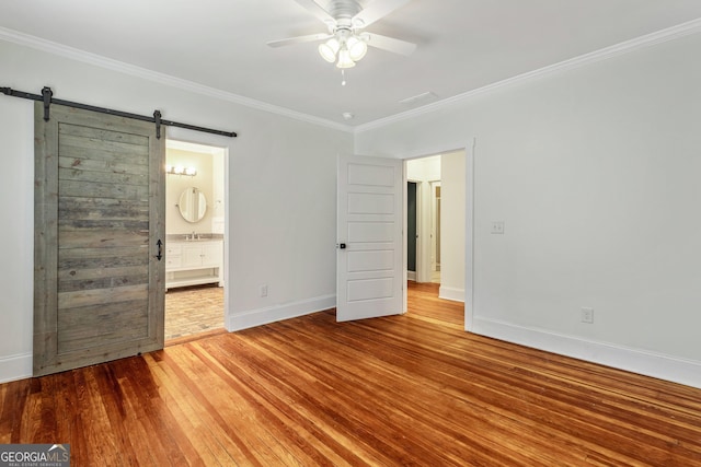 148 Jackson St, Newnan, GA 30263 - unfurnished bedroom with crown molding, wood-type flooring, baseboards, a barn door, and a sink