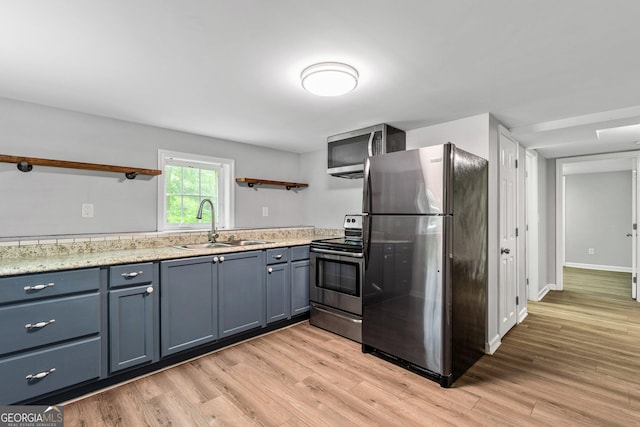 148 Jackson St, Newnan, GA 30263 - kitchen with open shelves, stainless steel appliances, a sink, light wood-style floors, and blue cabinets