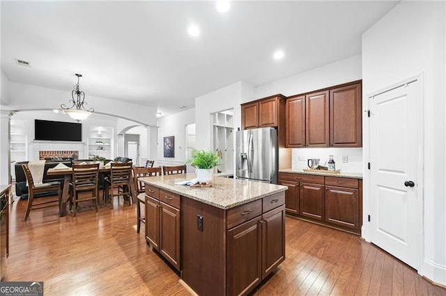 910 Ovalene Ln SW, Marietta, GA 30064 - kitchen with decorative columns, stainless steel fridge with ice dispenser, dark wood-type flooring, a kitchen island, and light stone counters