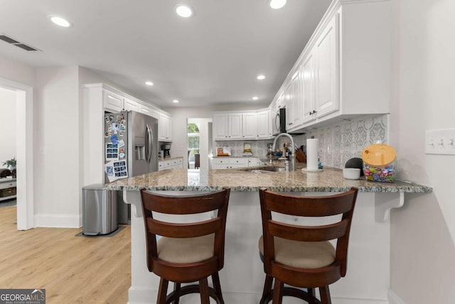 3652 Shady Oak Trl, Gainesville, GA 30506 - kitchen featuring a peninsula, decorative backsplash, recessed lighting, light wood-style floors, and light stone countertops