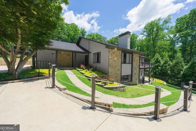 9701 Buice Rd, Alpharetta, GA 30022 - view of front facade with stone siding, a front yard, a chimney, and a balcony