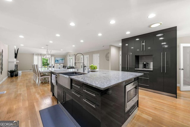 9701 Buice Rd, Alpharetta, GA 30022 - kitchen featuring a sink, modern cabinets, dark cabinets, light wood finished floors, and baseboards