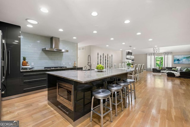 9701 Buice Rd, Alpharetta, GA 30022 - kitchen with wall chimney exhaust hood, a sink, stainless steel microwave, a breakfast bar area, and a spacious island