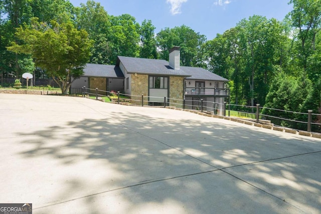 9701 Buice Rd, Alpharetta, GA 30022 - view of front of property with stone siding, a chimney, driveway, and view of scattered trees