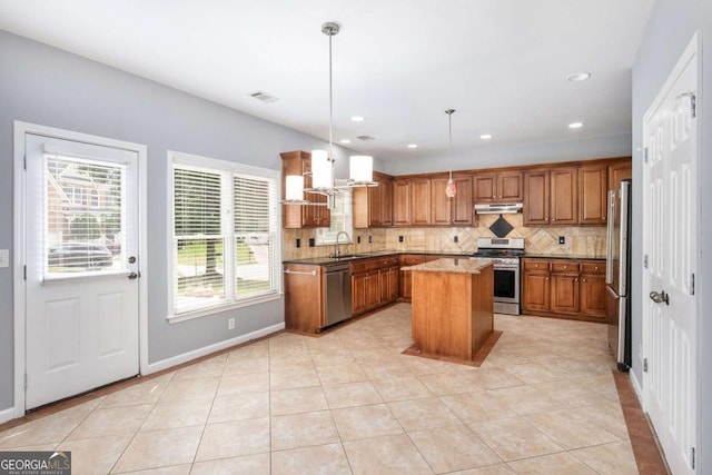 2023 Arbor Springs Way, Buford, GA 30519 - kitchen with appliances with stainless steel finishes, under cabinet range hood, brown cabinets, decorative backsplash, and a kitchen island