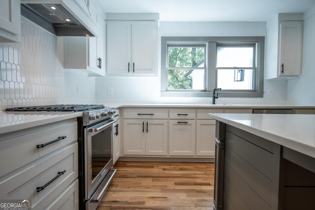 215 Holman Ave, Athens, GA 30606 - kitchen with high end range, premium range hood, light wood-style floors, light countertops, and backsplash
